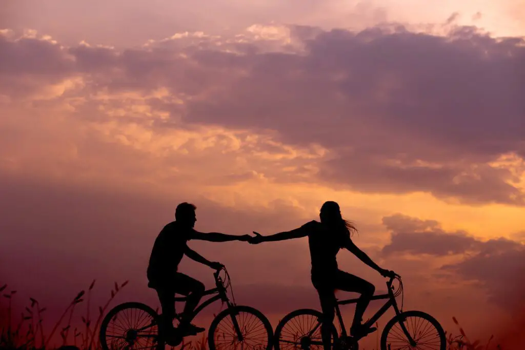 A man and a woman biking at sunset.