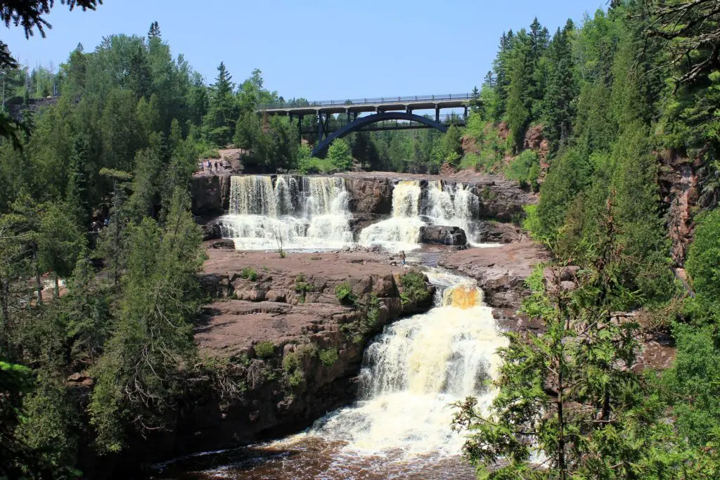 small waterfalls with a bridge in the background